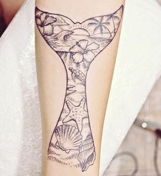 a tattoo on the arm of a woman with a mermaid tail and seashells