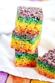 three pieces of rainbow cake sitting on top of a white napkin next to each other