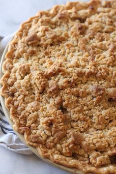 a pie sitting on top of a white plate covered in crumbly toppings