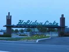 a large green sign that is on the side of a road in front of a building