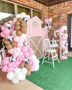 a party with balloons and farm animals on the grass in front of a barn door