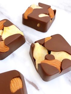 four pieces of chocolate with apples in them on a marble counter top and white background