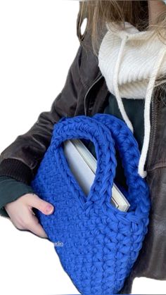 a woman holding a blue crocheted purse