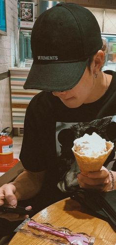 a person sitting at a table with an ice cream cone in their hand and some writing on it