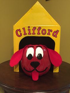 a red dog with a black hat on top of a wooden table next to a sign