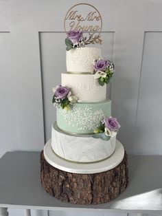 a three tiered wedding cake with purple flowers