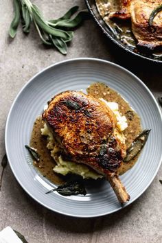 a plate with some meat and mashed potatoes on it next to a skillet