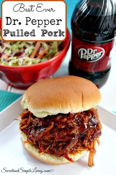 a pulled pork sandwich on a bun with coleslaw and soda in the background