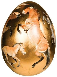 an easter egg with horses painted on it's side and gold foiling around the edges