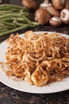 a white plate topped with fried food next to green beans and mushrooms on a table