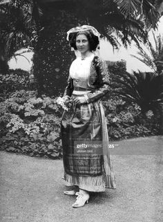 a woman in an old fashion dress and hat poses for the camera with her hands on her hips