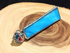 a blue tie bar sitting on top of a piece of wood next to a ring