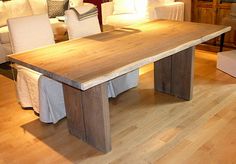 a wooden table sitting in the middle of a living room with white chairs around it