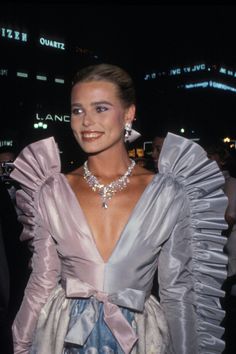 a woman in a dress and necklace posing for the camera