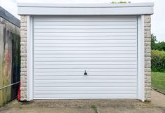 a white garage door is open in front of a brick wall and green grass behind it