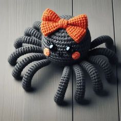 a crocheted spider with a bow on it's head sitting on a wooden surface