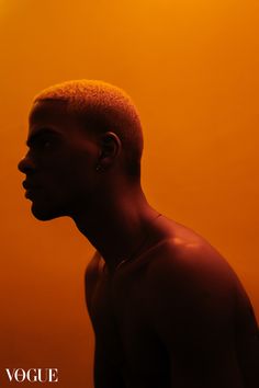 a man with ear piercings standing in front of an orange background