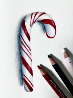 some pencils are laying next to a drawing of a candy cane with red and white stripes