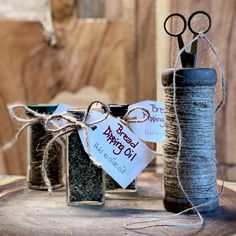 two jars filled with different types of spices and scissors on top of a wooden table