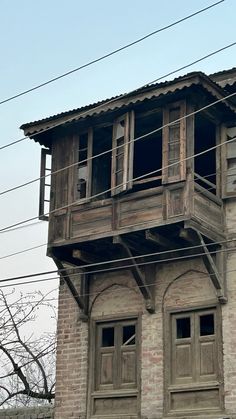 an old brick building with wooden windows and balconies on the top floor, in front of power lines