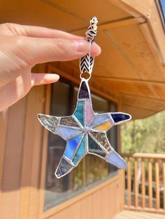 a hand holding a star shaped glass ornament in the shape of a flower