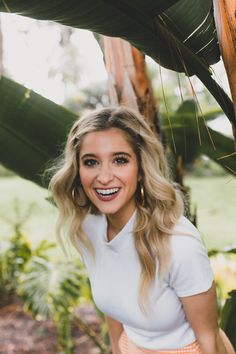 a woman standing under a palm tree smiling