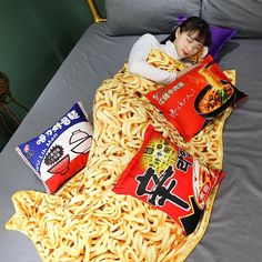 a woman laying on top of a bed covered in lots of noodles and other foods