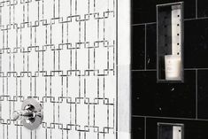 a black and white tiled wall next to a toilet paper dispenser with a candle in it