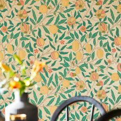 the wall paper has lemons on it and is next to a vase with flowers