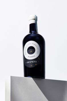 a bottle of dark colored wine sitting on top of a white box with a black cap