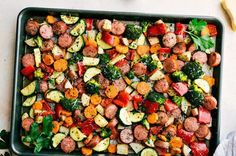 a pan filled with sausage and veggies on top of a table