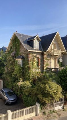 a car is parked in front of a house with vines growing on it's roof