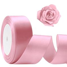 two rolls of pink satin ribbon next to a rose