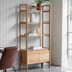 a wooden shelf with two vases on top of it and a chair next to it