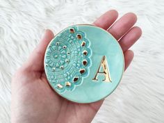 a hand holding a blue plate with gold letters on it