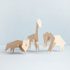 three wooden giraffes standing next to each other on a white table top