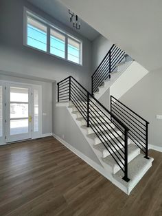 an empty living room with stairs leading up to the second floor and another door in the background