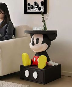 a woman sitting in a chair next to a mickey mouse figurine