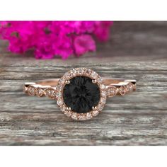 a black and white diamond ring on top of a wooden table with pink flowers in the background