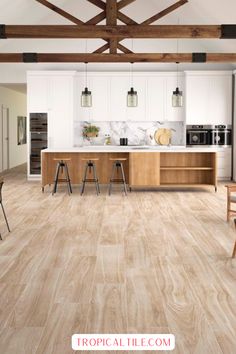 an open kitchen and dining room with wood flooring, white walls and ceiling beams