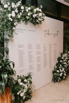 the seating chart is set up with greenery and white flowers