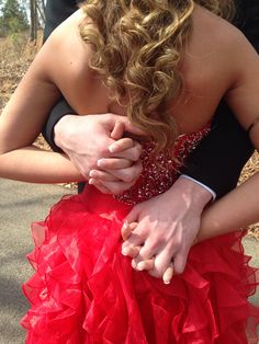 a woman in a red dress holding the hand of a man