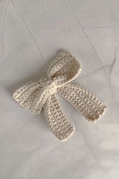 a crocheted bow on a white marble counter top, with one knot in the middle