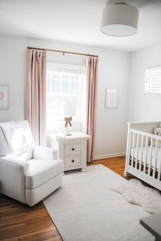 a baby's room with a white crib, chair and window in the corner