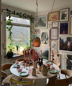 a dining room table with candles and pictures on the wall in front of it,