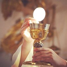 a woman holding a chalice in her hands with the light shining on her face