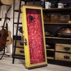 an open case sitting on top of a hard wood floor next to guitars and other musical equipment