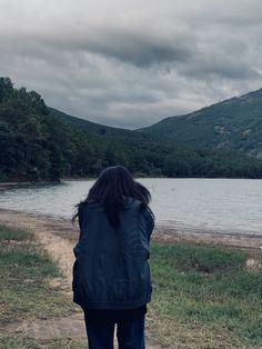 a woman standing on the shore of a lake