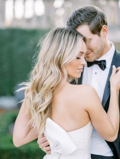 a man in a tuxedo and a woman in a white dress are embracing each other