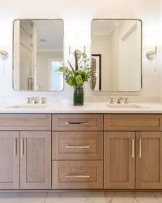 a bathroom with double sinks and two mirrors on the wall next to eachother